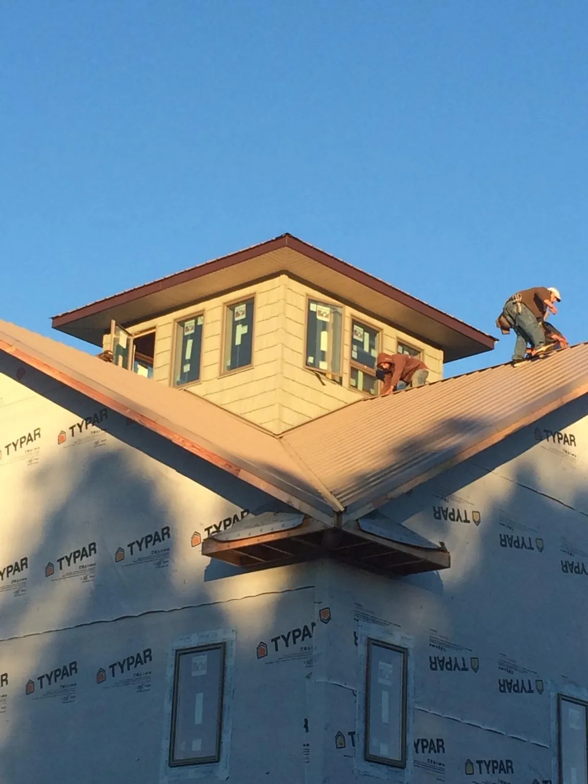 Roofers working around a rooftop cupola on a new metal roof at sunset — Roof Waterproofing in Georgetown by Roofing Brothers